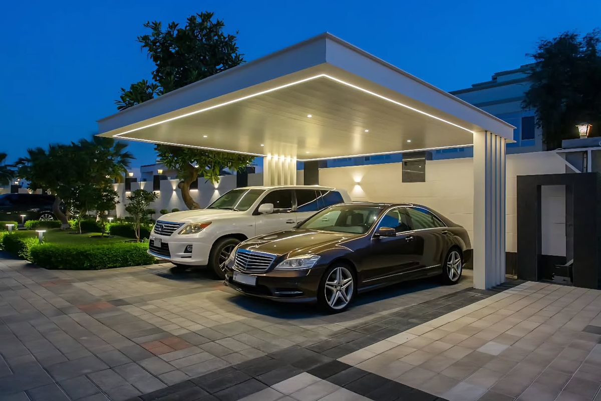 Single-bay carport with bright LED ceiling strip at blue hour with two vehicles.