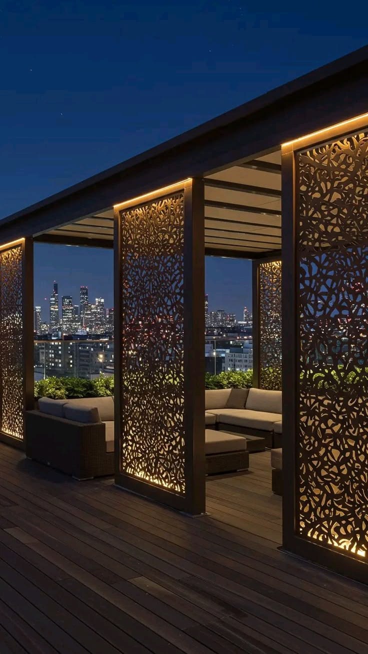 Laser-cut aluminium mashrabiya privacy panels with internal LED glow on a rooftop overlooking the city skyline.